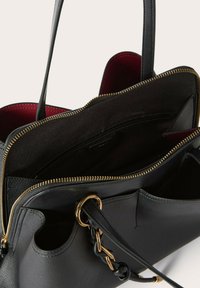 Borsa a tracolla nera in pelle con zip dorata, fodera interna rossa e accento a catena. Presenta un interno spazioso con più scomparti.