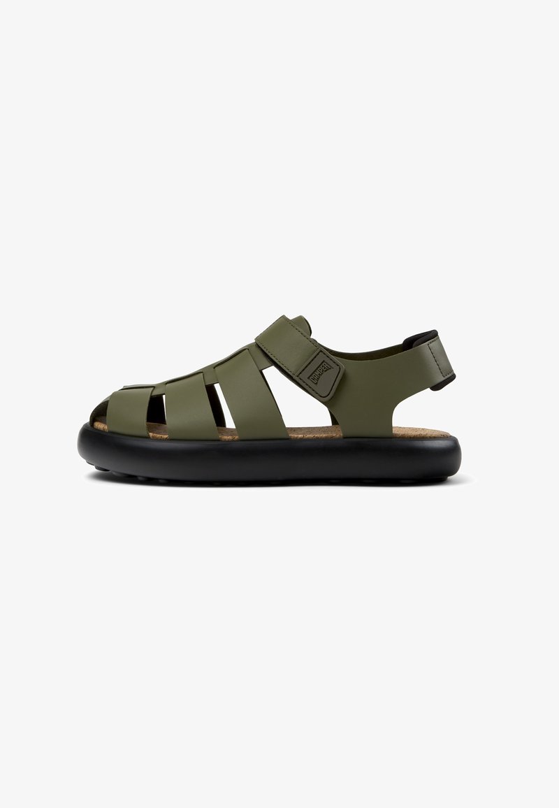 Green synthetic sandal featuring multiple strap design, adjustable ankle strap, black sole, and textured cork footbed for comfort.
