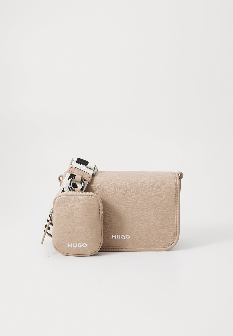 Beige skinnveske med crossbody-design og avtakbar liten pose. Har hvit "HUGO" logo og mønstret justerbar stropp. Glatt tekstur.