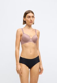 Minkštas švelnios violetinės spalvos liemenėlė su lankeliais ir plačiomis petnešėlėmis, derinama su juodais be siūlių kelnaitėmis. Lygus paviršius ir klasikinis dizainas kasdieniam dėvėjimui.