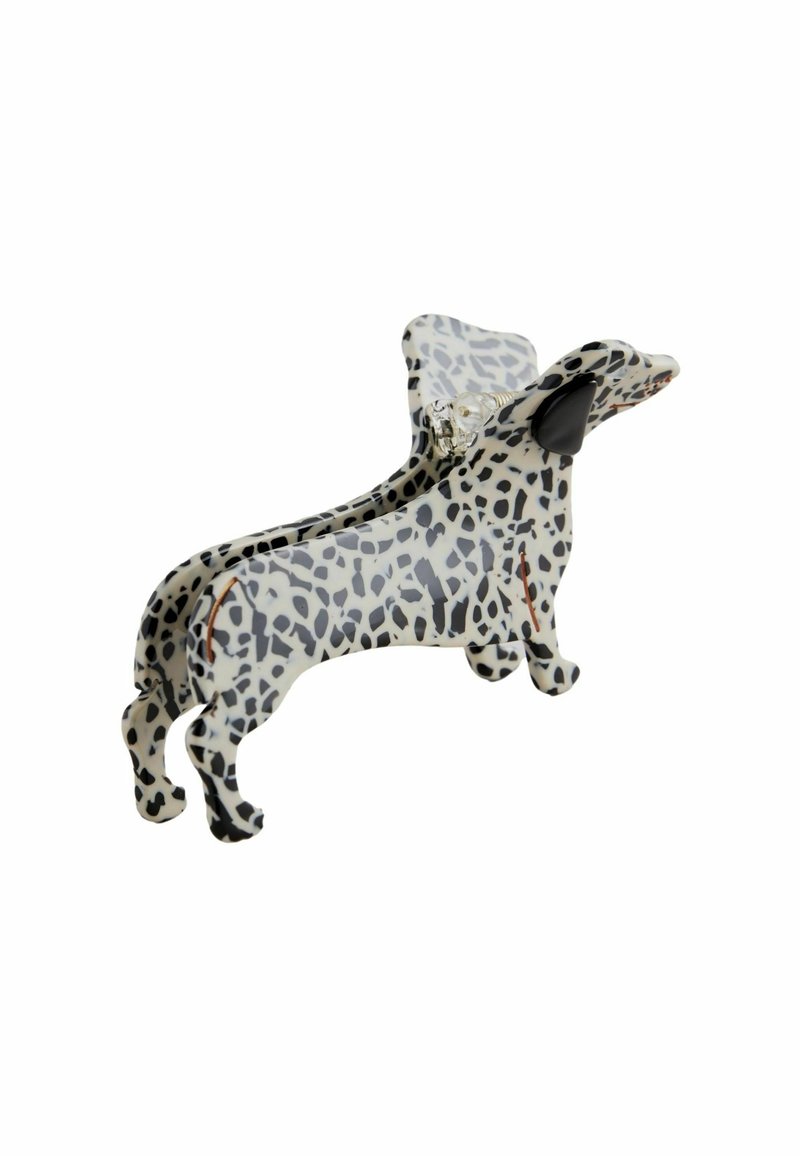 En klämma formad som en tax, tillverkad av ett glänsande material, med en vit bas och svarta fläckar samt detaljerade öron. Designen betonar den lekfulla formen.