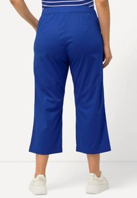 Blåcroppade byxor med elastisk midja, lättviktig tyg och sidsprund, kombinerade med vita sneakers.