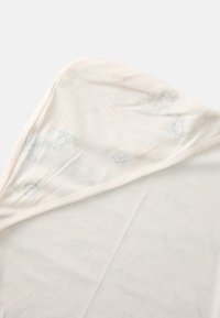 Couverture pour bébé en coton d'une douce couleur crème. Présente des motifs d'animaux imprimés subtils dans des tons pastels et une finition texturée. Bords arrondis.