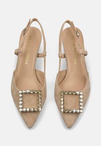 Décolleté slingback in suede beige con punta affilata, impreziosito da una fibbia quadrata di strass e da un delicato cinturino alla caviglia.