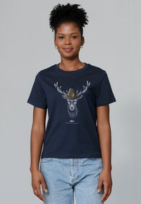 T-shirt en coton navy affichant un graphique d'un cerf avec des bois portant un chapeau. Manches courtes, col rond et coupe décontractée.