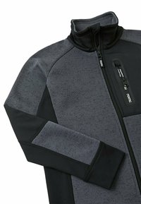 Giacca in pile con zip in grigio scuro e nero. Presenta un colletto alto, tessuto testurizzato e pannelli a contrasto sulle maniche. Dettaglio con tasca con zip.