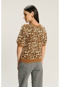 Sweter z krótkim rękawem w panterkę w kolorze brązowym i kremowym, z prążkowanym okrągłym dekoltem i dopasowanym wykończeniem. Miękki, teksturowany materiał dziany.