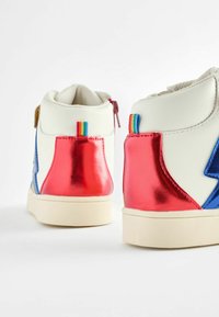 Valged kõrge sääre sneakersid metalliliste punaste ja siniste detailidega, millel on tekstuuriga viimistlus ja vikerkaare triipudega silt kanna peal.
