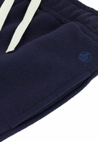 Shorts de sport bleu marine en tissu texturé, dotés d'un cordon blanc et d'un petit logo bleu sur le devant.