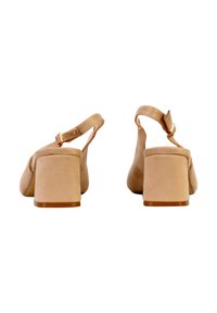 Paire de sandales à talons blocs en suède beige avec des brides de cheville et des boucles dorées, vues de dos sur un fond blanc.