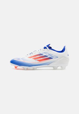 Scarpe da calcio bianche e blu con una tomaia testurizzata, caratterizzate da accenti rossi e una suola sagomata con tacchetti visibili per la trazione.
