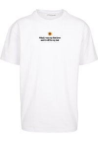 T-shirt en coton blanc avec un logo noir rond et du texte noir indiquant "La musique a été mon premier amour et elle sera mon dernier."