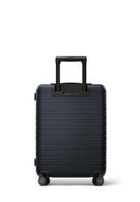 Valise rigide navy avec un design texturé à rainures, une poignée rétractable et quatre roues pour une meilleure mobilité. Pas de logos ni d'accents visibles.