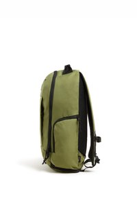 Mochila de tela verde con detalles en negro, que cuenta con un bolsillo frontal con cremallera, un lateral de malla y correas de hombro acolchadas para mayor comodidad.
