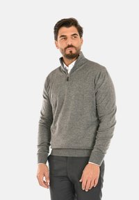 Maglione grigio con zip al collo, realizzato in un tessuto morbido, con polsini e orlo a coste, e un colletto in un colore contrastante sotto.