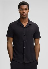 Schwarzes Kurzarmhemd mit strukturierter Oberfläche, mit Knopfverschluss vorne, klassischem Kragen und lässiger Passform.