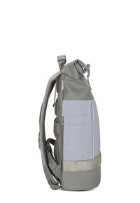 Mochila gris con diseño de rollo, materiales mixtos, correas de malla y bolsillo frontal. Presenta una base plana y una paleta de colores minimalista.