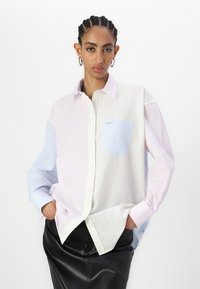 Multicolored striped shirt featuring pink, blue, and white panels, button-up design, and a small chest pocket with brand logo.