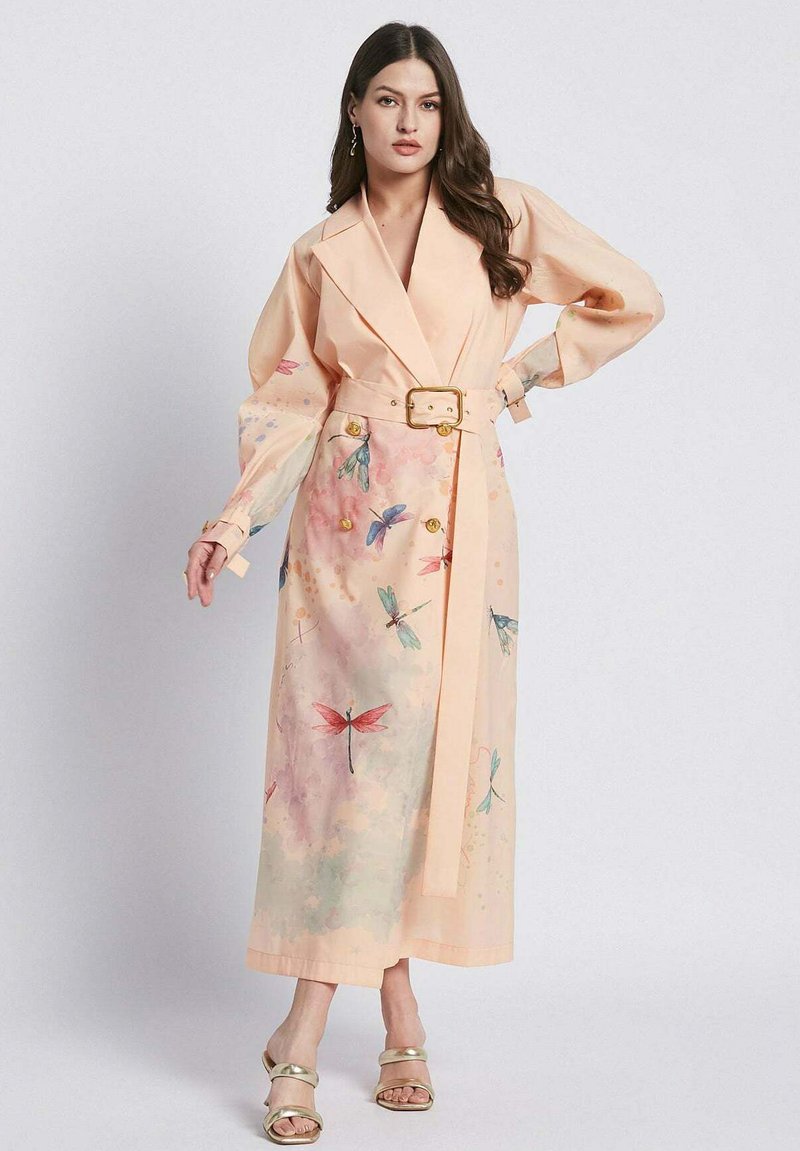 Vestito avvolgente color pesca con maniche lunghe, caratterizzato da una vita con cintura, motivi floreali di libellule e bottoni dorati. Tessuto morbido e leggero.