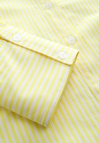 Gelb-weißer gestreifter Hemd mit Knopf-Design, ausgestattet mit weißen Knöpfen, glattem Stoff und sauber genähten Manschetten.