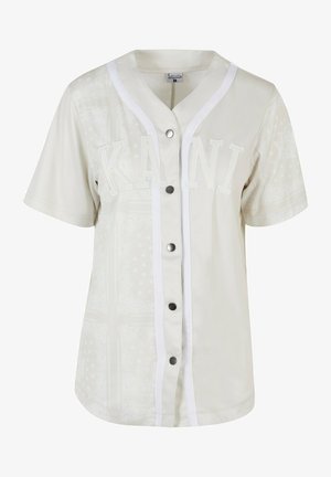Korte mouwen, lichtbeige honkbalshirt met witte biezen, met het woord "KANI" in reliëfletters en decoratieve patronen. Vijfknopen voorkant.