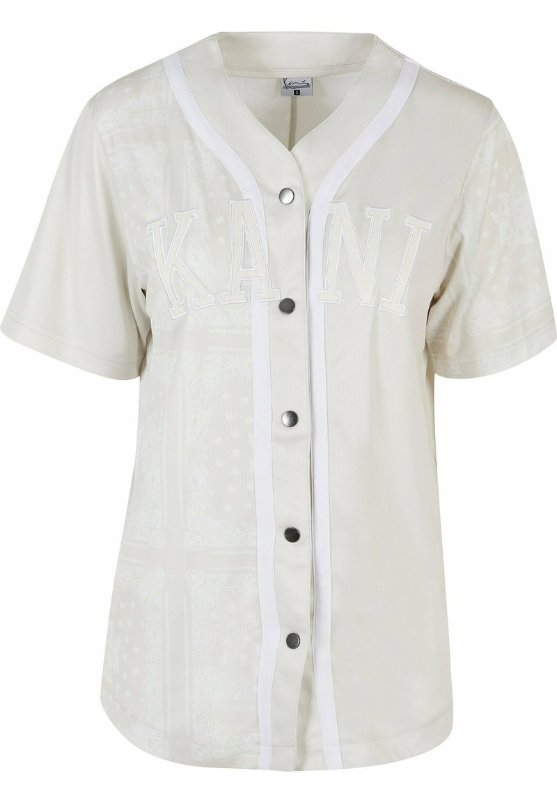 Kortærmet, lyse beige baseball-style skjorte med hvid kant, der har ordet "KANI" i hævede bogstaver og dekorative mønstre. Fem-knappers lukning foran.