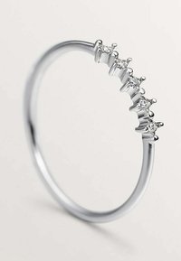 Anillo de plata con cinco piedras preciosas brillantes engastadas en una banda texturizada, que se estrecha suavemente hasta una forma circular pulida y minimalista.