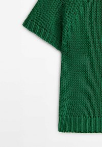 Pull court vert en maille avec poignets et ourlet côtelés, présentant un motif en grosse maille sur fond blanc.
