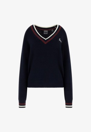 Pull à col en V bleu marine avec des rayures blanches et bordeaux au col et aux poignets, manches longues, et petit logo brodé sur la poitrine.