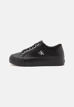 Czarny niski, skórzany sneaker z sznurowadłami, grubą podeszwą, futrzaną wyściółką i logo Calvin Klein po bokach.