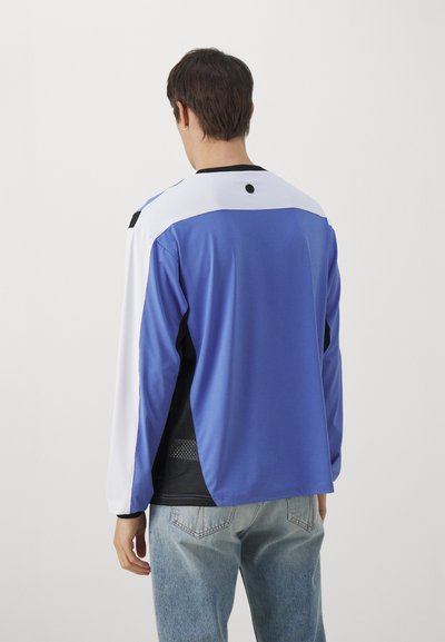 Blue long-sleeve shirt with white and black accents, featuring a mesh texture on the sides and a round black detail at the back neckline.