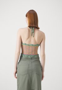 Haut de bikini au crochet avec des rayures vertes, roses et jaunes ; présente un bord texturé et festonné et se noue au cou. Assorti à une jupe verte.
