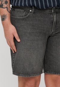 Sive jeans kratke hlače z ohlapnim krojem, zasnovo s petimi žepi in vidno šivanko. Imajo pas z gumbom in zadrgo.
