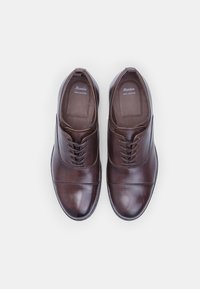 Chaussures en cuir marron avec une finition lisse, bout rond et design à laçage. Présentent des coutures subtiles et des semelles plates pour la stabilité.