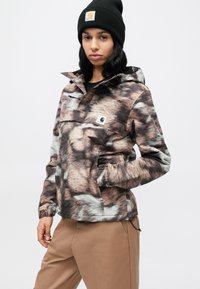 Μπουφάν πεζοπορίας με καφέ και γκρι γούνα, διαθέτει μπροστινή τσέπη με φερμουάρ, ρυθμιζόμενο κουκούλι και ελαστικά μανίκια. Συνδυάζεται με παντελόνι ταμπά.