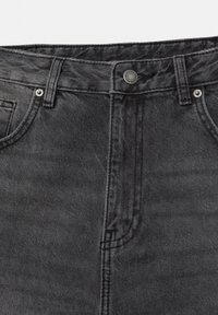 Nahaufnahme schwarzer Jeans aus Denim mit Fokus auf Bund, Knopf, Gürtelschlaufen und vordere Taschen.