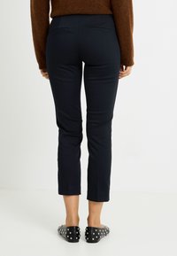 Pantalones cortos azul marino con una textura suave, que cuentan con dos bolsillos traseros y un corte entallado. Combinados con bailarinas negras con tachuelas.