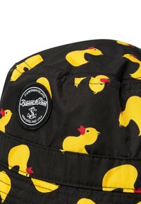 Black bucket hat with a pattern of yellow rubber ducks. Features a round logo patch with white text on the side. Material appears lightweight and water-resistant.