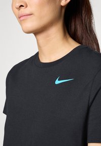 Musta puuvillainen t-paita, jossa on pyöreä kaula-aukko ja lyhyet hihat. Vasemmassa rintapielessä on vaaleansininen Nike-logon.