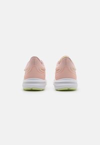 Baskets de sport rose clair avec une tige texturée, semelles blanches et accents vert pâle. Caractéristiques d'un dos rembourré et d'un design multicouche.