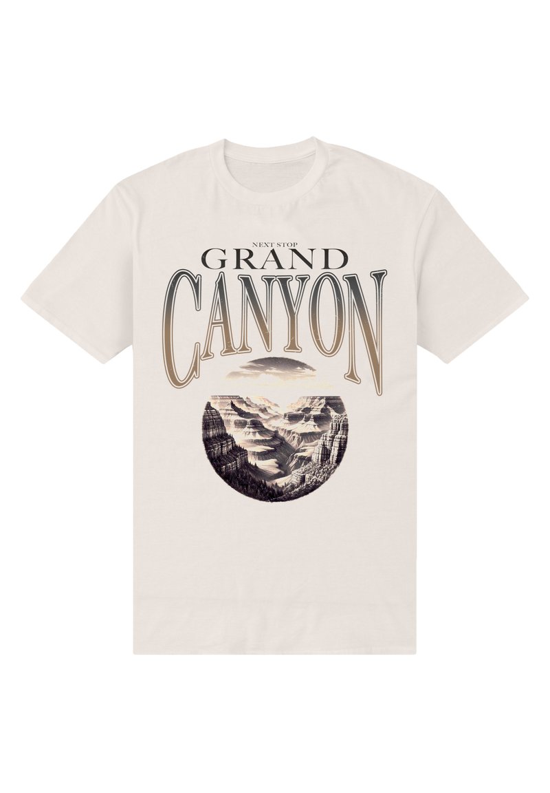 Cremefarvet t-shirt med et rundt grafisk billede af Grand Canyon, med sort tekst ovenfor og nedenfor, der forestiller bjerglandskaber.
