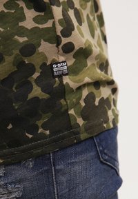 Lyhyet hihaiset camo-kuosiset paidat vihreän ja beigen sävyissä, jossa on ommeltu helma ja G-Star-tunnus sivussa.