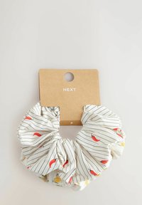 Balts audums scrunchie ar sarkano čili un dzelteno ziedu rakstiem, ar pārmaiņus plānām melnām svītrām, pievienots kartona birkai.