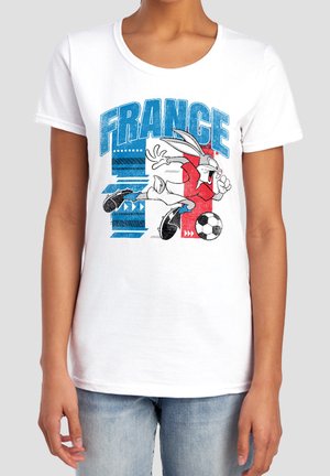 Weißes T-Shirt mit einem Cartoon-Hasen, der einen Fußball kickt, blauer Text mit "FRANCE" auf blau-rot gestreiftem Hintergrund.