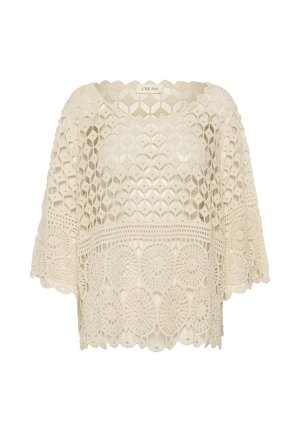 Crèmekleurige gehaakte kanten blouse met wijde mouwen en geometrische en cirkelvormige patronen, met het label "CREAM" bij de halslijn.