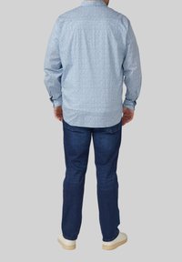 Lichtblauw overhemd met een klein bloemenpatroon, button-down kraag, lange mouwen, gecombineerd met donkerblauwe spijkerbroek en witte sneakers.