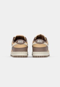 Nike sneakers világosbarna és barna színkombinációban, texturált bőr felsőrésszel, párnázott bokarésszel és látható futóprofilú gumitalppal.