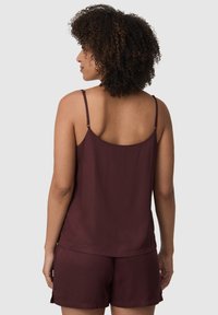 Bordeaux slaapset met een mouwloze top met verstelbare bandjes en bijpassende shorts; soepel materiaal met een relaxte fit en minimaal ontwerp.