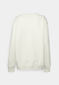 Felpa oversize color crema con scollatura rotonda, spalle cadute e polsini a costine. Texture liscia, senza loghi o motivi visibili.