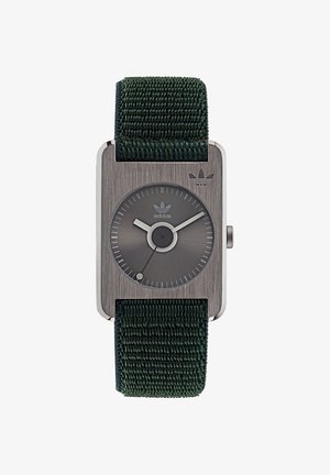 Vierkante horloge met een donkergrijze metalen kast, grijze wijzerplaat en een groene, geweven stoffen band. Bevat minimalistische uurmarkeringen en een Adidas-logo.